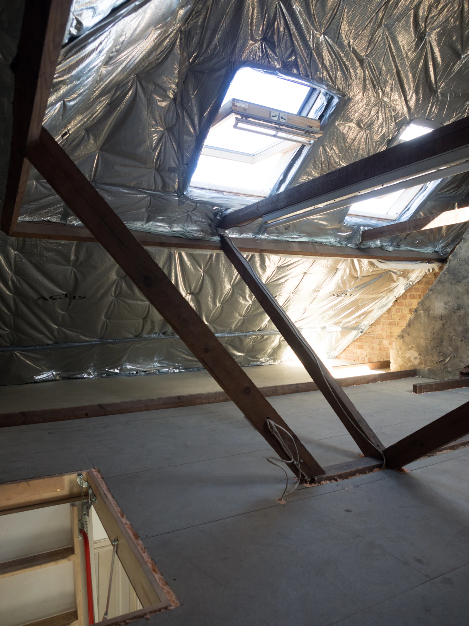 A roofline cross-section showing blown-in insulation being installed across an attic floor